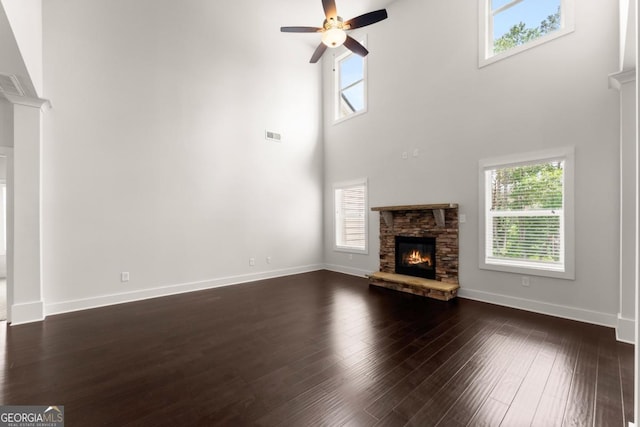 2855 Pilgrim Mill Rd, Cumming, GA 30041 - unfurnished living room featuring ceiling fan, a stone fireplace, a high ceiling, dark wood-style floors, and baseboards