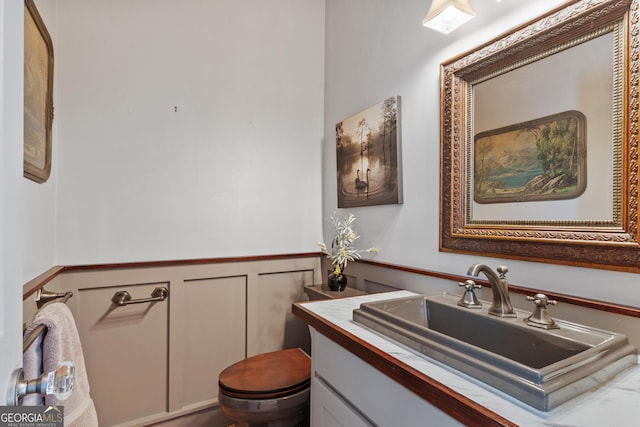 3498 Overland Trl, Ellenwood, GA 30294 - bathroom featuring toilet, a wainscoted wall, vanity, and a decorative wall