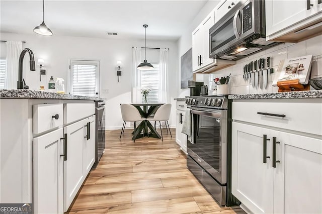 1363 Cooper Springs Rd, Grayson, GA 30017 - kitchen featuring stainless steel appliances, tasteful backsplash, light wood-style flooring, and light stone counters