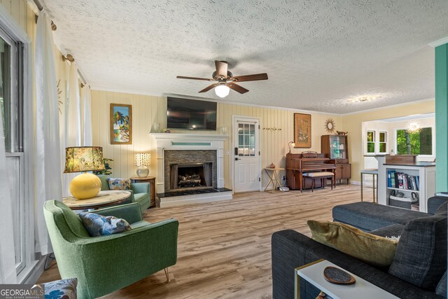 534 Mountainside Dr, Rabun Gap, GA 30568 - living room featuring a ceiling fan, crown molding, wood finished floors, a textured ceiling, and a stone fireplace