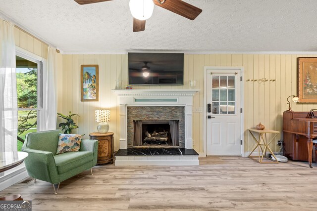534 Mountainside Dr, Rabun Gap, GA 30568 - living area with a textured ceiling, ornamental molding, ceiling fan, wood finished floors, and a fireplace with raised hearth