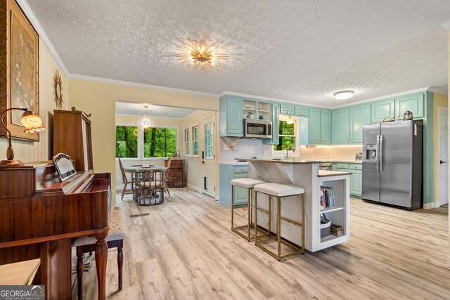 534 Mountainside Dr, Rabun Gap, GA 30568 - kitchen with stainless steel appliances, healthy amount of natural light, light wood-style floors, a textured ceiling, and a kitchen bar
