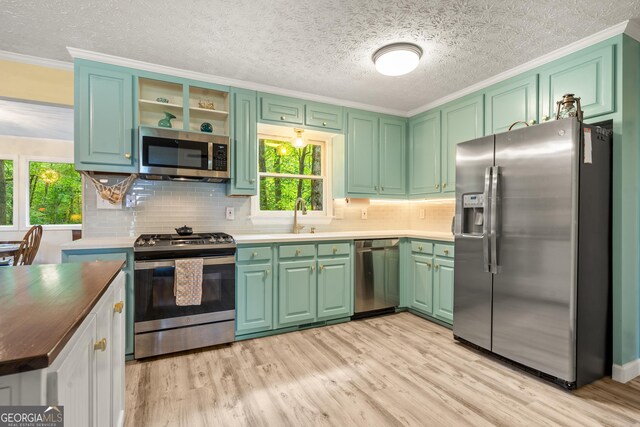 534 Mountainside Dr, Rabun Gap, GA 30568 - kitchen with appliances with stainless steel finishes, light wood-type flooring, plenty of natural light, backsplash, and crown molding