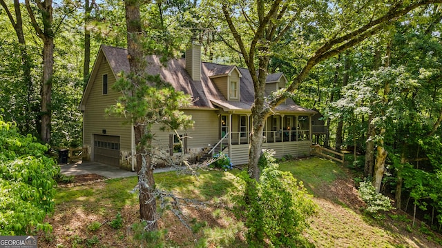 534 Mountainside Dr, Rabun Gap, GA 30568 - view of front of home featuring a sunroom, an attached garage, driveway, a chimney, and view of wooded area