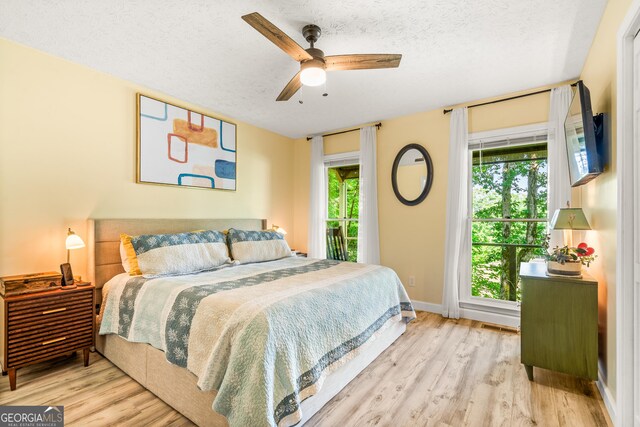 534 Mountainside Dr, Rabun Gap, GA 30568 - bedroom featuring multiple windows, wood finished floors, a textured ceiling, and access to exterior