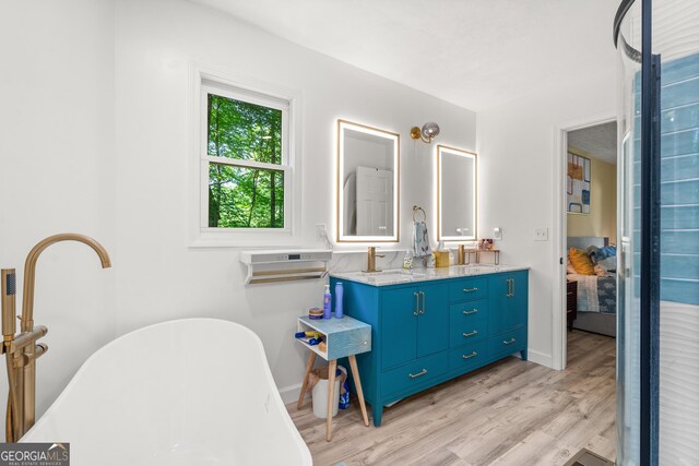 534 Mountainside Dr, Rabun Gap, GA 30568 - ensuite bathroom featuring double vanity, a freestanding bath, wood finished floors, and baseboards