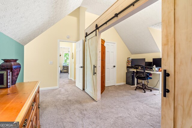 534 Mountainside Dr, Rabun Gap, GA 30568 - office area featuring a textured ceiling, lofted ceiling, carpet flooring, a barn door, and baseboards