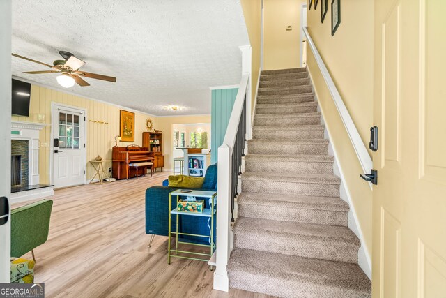 534 Mountainside Dr, Rabun Gap, GA 30568 - staircase featuring wood finished floors, ceiling fan, crown molding, a textured ceiling, and a fireplace