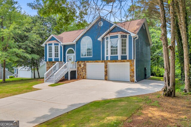 1407 Water Wheel Dr, Bethlehem, GA 30620 - bi-level home featuring driveway, stone siding, a garage, stairs, and a front yard