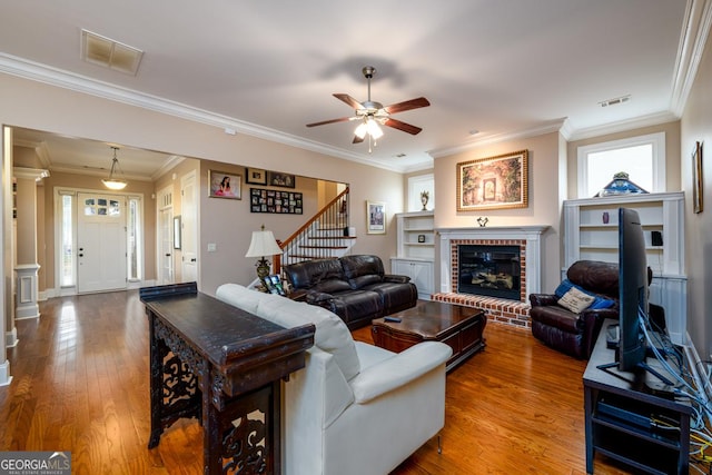 13042 Dartmore Ave, Alpharetta, GA 30005 - living room with stairway, ceiling fan, wood finished floors, ornamental molding, and a brick fireplace