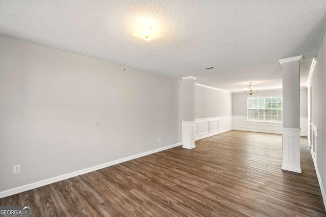 3731 Laramie Rd, Ellenwood, GA 30294 - unfurnished room featuring a chandelier, a textured ceiling, dark wood finished floors, ornate columns, and crown molding