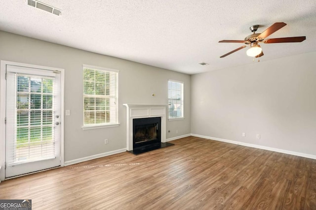 3731 Laramie Rd, Ellenwood, GA 30294 - unfurnished living room featuring wood finished floors, a textured ceiling, a ceiling fan, healthy amount of natural light, and a fireplace with raised hearth