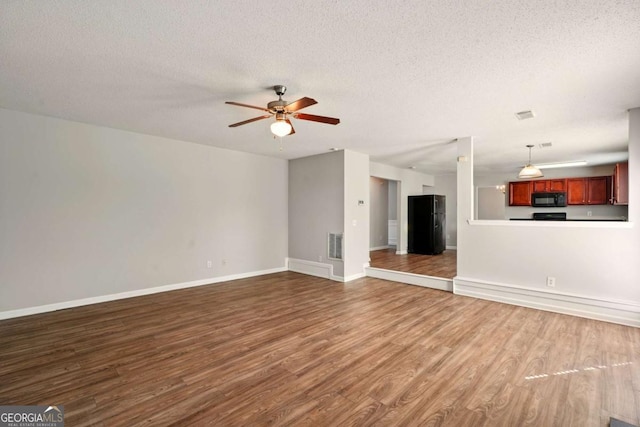 3731 Laramie Rd, Ellenwood, GA 30294 - unfurnished living room with wood finished floors, a ceiling fan, a textured ceiling, and baseboards