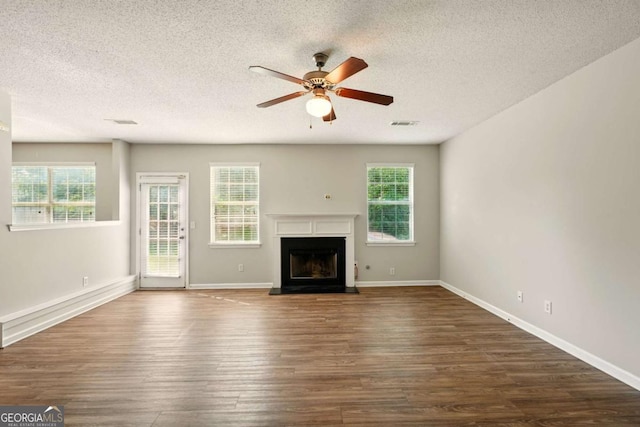 3731 Laramie Rd, Ellenwood, GA 30294 - unfurnished living room with ceiling fan, a textured ceiling, dark wood finished floors, healthy amount of natural light, and a fireplace