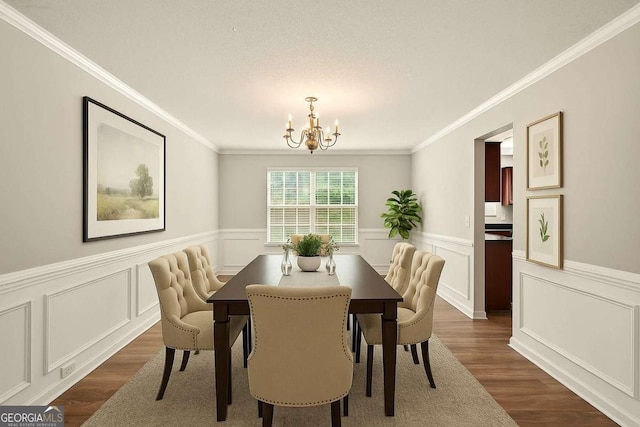 3731 Laramie Rd, Ellenwood, GA 30294 - dining space featuring a chandelier, dark wood-style flooring, wainscoting, ornamental molding, and a decorative wall