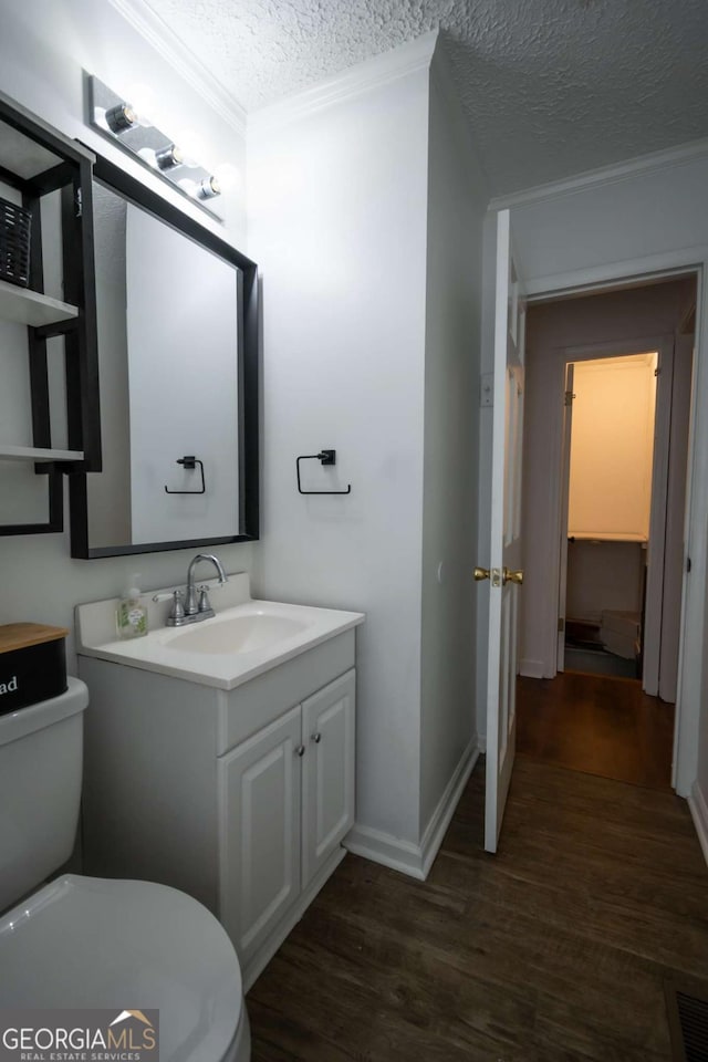 2060 Simonton Bridge Rd, Watkinsville, GA 30677 - half bathroom featuring ornamental molding, toilet, vanity, a textured ceiling, and wood finished floors