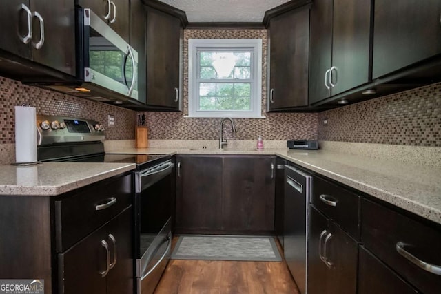 2060 Simonton Bridge Rd, Watkinsville, GA 30677 - kitchen featuring appliances with stainless steel finishes, a sink, wood finished floors, tasteful backsplash, and dark brown cabinets
