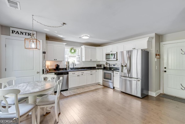 6540 Terracewood Ln, Gainesville, GA 30506 - kitchen featuring stainless steel appliances, dark countertops, a sink, white cabinetry, and wood finished floors