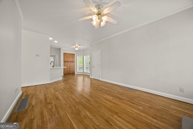 85 Bloomfield Way, Sharpsburg, GA 30277 - unfurnished living room featuring ceiling fan, baseboards, wood finished floors, crown molding, and a sink