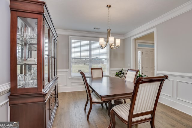 895 Lillian Park Dr, Grovetown, GA 30813 - dining space with a chandelier, wainscoting, a decorative wall, wood finished floors, and crown molding