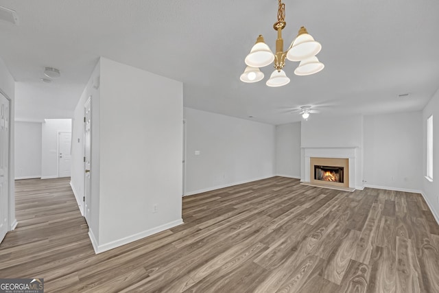 7459 Old Chapel, South Fulton, GA 30349 - unfurnished living room featuring wood finished floors, a chandelier, a ceiling fan, and a warm lit fireplace