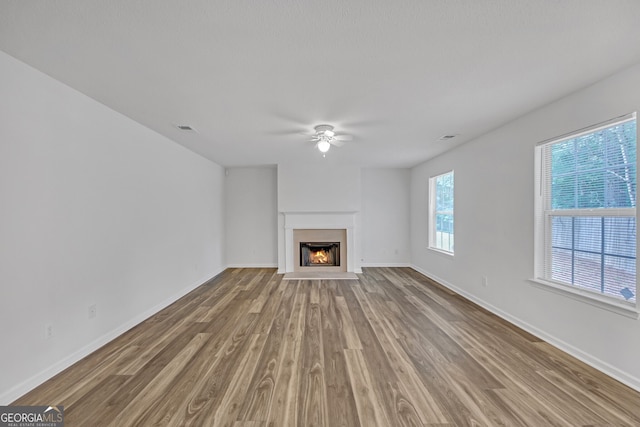 7459 Old Chapel, South Fulton, GA 30349 - unfurnished living room featuring a ceiling fan, wood finished floors, and a warm lit fireplace