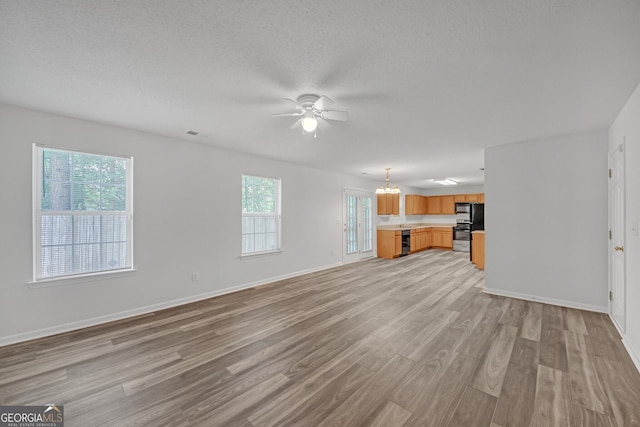 7459 Old Chapel, South Fulton, GA 30349 - unfurnished living room featuring light wood finished floors, ceiling fan, a chandelier, and a textured ceiling