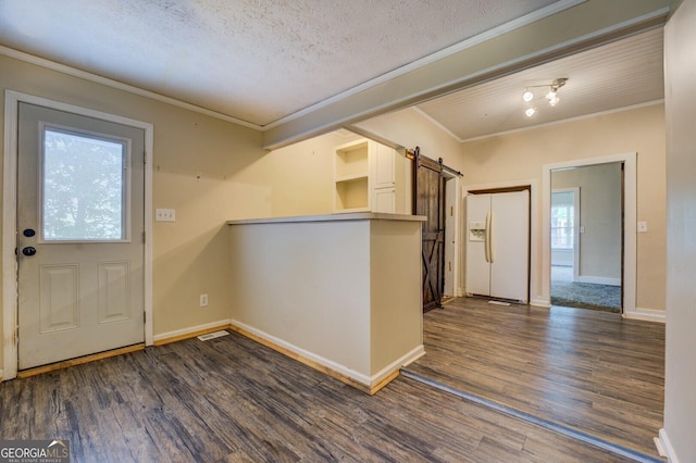 6 Mill St, Jackson, GA 30233 - kitchen with white refrigerator with ice dispenser, a barn door, dark wood finished floors, crown molding, and baseboards