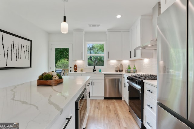 102 Rockyford Rd, Atlanta, GA 30317 - kitchen featuring stainless steel appliances, wall chimney exhaust hood, light wood-style flooring, white cabinets, and tasteful backsplash
