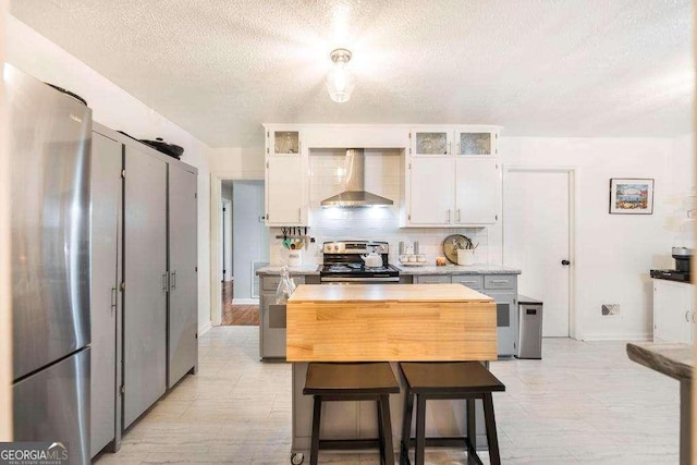 913 7th Ave, Albany, GA 31701 - kitchen featuring wall chimney range hood, appliances with stainless steel finishes, a textured ceiling, light countertops, and white cabinetry