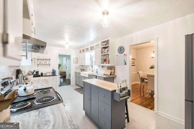 913 7th Ave, Albany, GA 31701 - kitchen with open shelves, a textured ceiling, white cabinets, light countertops, and gray cabinetry