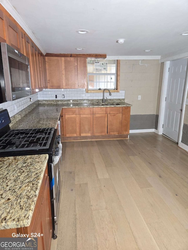 2812 Maple Rd SE, Rome, GA 30161 - kitchen with stainless steel appliances, light wood-type flooring, a sink, light stone counters, and brown cabinetry