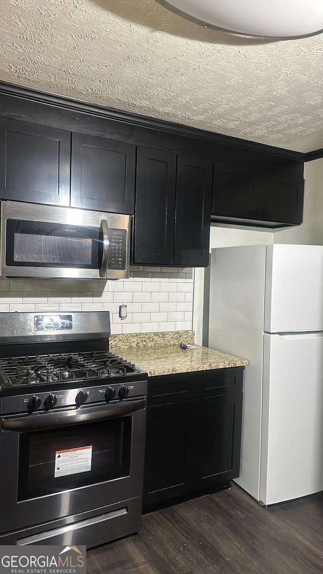 2812 Maple Rd SE, Rome, GA 30161 - kitchen with black gas stove, freestanding refrigerator, dark cabinets, stainless steel microwave, and dark wood-style flooring