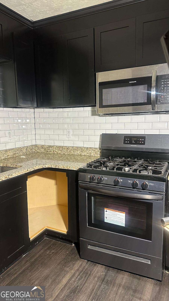 2812 Maple Rd SE, Rome, GA 30161 - kitchen with stainless steel microwave, black gas range, backsplash, dark cabinets, and dark wood-style flooring