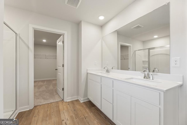 4036 Trimrose Ct Unit 70, Atlanta, GA 30349 - bathroom with a walk in closet, a shower stall, wood finished floors, double vanity, and recessed lighting