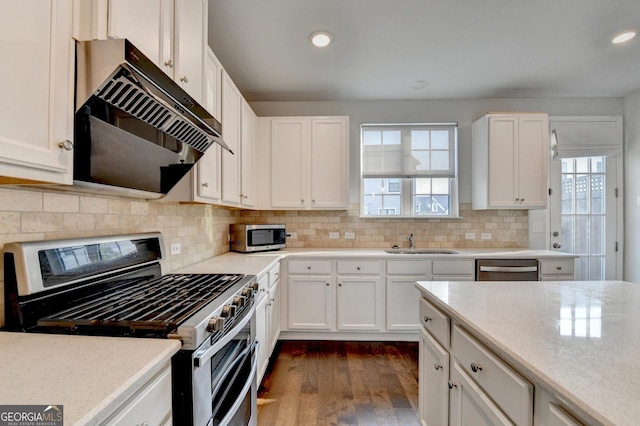 3360 Pickens St, Duluth, GA 30096 - kitchen with appliances with stainless steel finishes, under cabinet range hood, dark wood-style floors, a sink, and white cabinetry