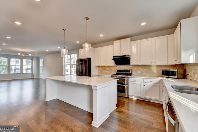 3360 Pickens St, Duluth, GA 30096 - kitchen with appliances with stainless steel finishes, a sink, under cabinet range hood, a kitchen island, and decorative backsplash