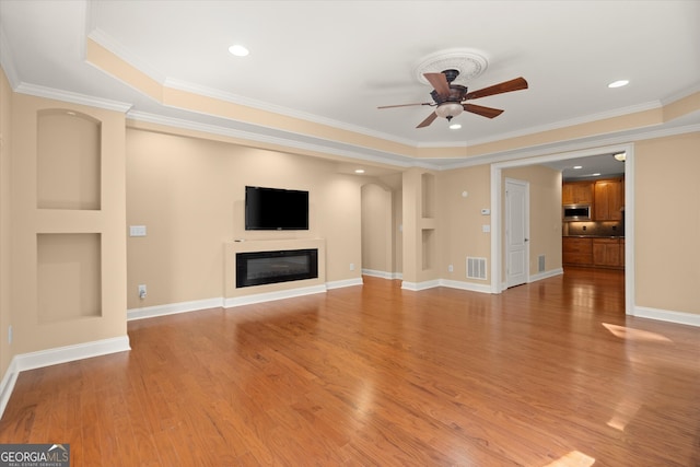 10565 Highgate Manor Ct, Duluth, GA 30097 - unfurnished living room with ceiling fan, light wood finished floors, a glass covered fireplace, crown molding, and arched walkways
