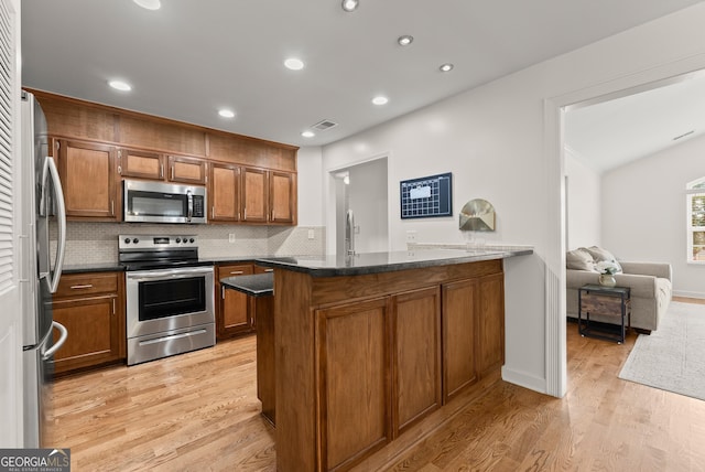 2605 Fort Apachee Trl, Dacula, GA 30019 - kitchen featuring stainless steel appliances, a peninsula, brown cabinetry, light wood-type flooring, and decorative backsplash