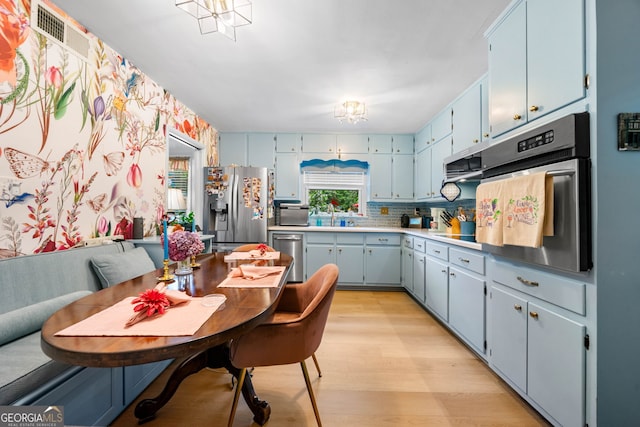 1138 Berkeley Rd, Avondale Estates, GA 30002 - kitchen featuring appliances with stainless steel finishes, light wood-style flooring, blue cabinetry, and decorative backsplash