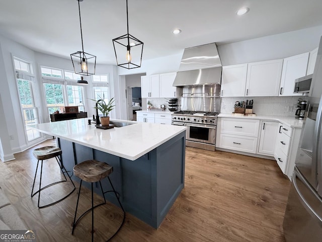 128 Golden Hills Dr, Woodstock, GA 30189 - kitchen with appliances with stainless steel finishes, wall chimney range hood, decorative backsplash, a center island, and a breakfast bar
