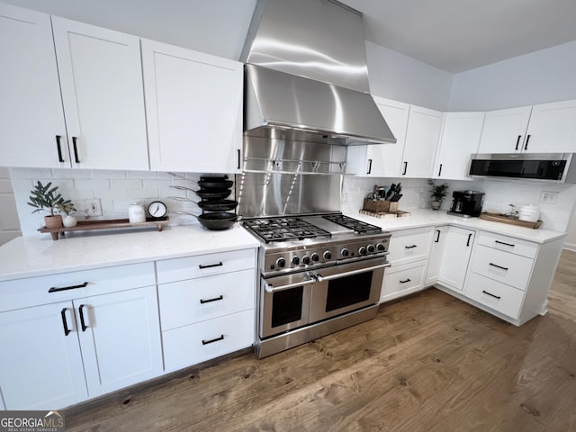 128 Golden Hills Dr, Woodstock, GA 30189 - kitchen with appliances with stainless steel finishes, wall chimney exhaust hood, dark wood-style flooring, backsplash, and white cabinets