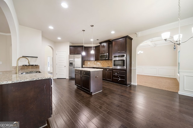 212 Jetta Cir, Mcdonough, GA 30253 - kitchen featuring appliances with stainless steel finishes, arched walkways, a chandelier, dark brown cabinetry, and light stone counters