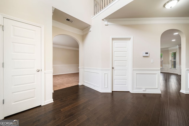 212 Jetta Cir, Mcdonough, GA 30253 - spare room featuring arched walkways, ornamental molding, a wainscoted wall, dark wood-style floors, and a decorative wall