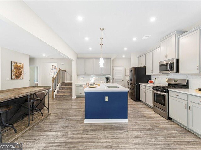340 Louise Ln, Canton, GA 30114 - kitchen with stainless steel appliances, a sink, backsplash, light wood-type flooring, and a kitchen island with sink