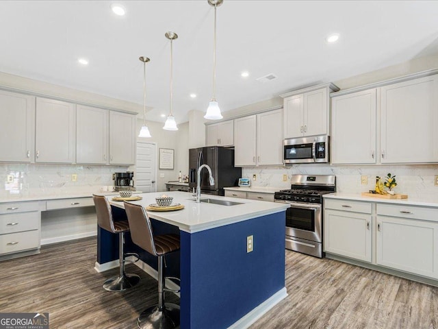 340 Louise Ln, Canton, GA 30114 - kitchen featuring stainless steel appliances, a sink, decorative backsplash, an island with sink, and wood finished floors
