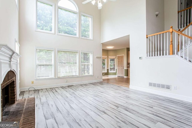 4045 Hillcrest View Ct, Suwanee, GA 30024 - unfurnished living room with a high ceiling, a ceiling fan, a fireplace, wood finished floors, and stairway