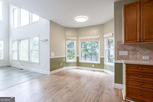 4045 Hillcrest View Ct, Suwanee, GA 30024 - kitchen with light wood-style flooring, brown cabinetry, decorative backsplash, light countertops, and baseboards