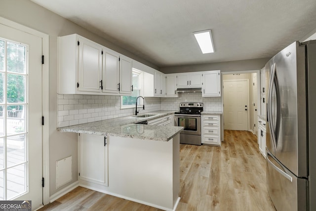 870 Rutherford Dr, Dacula, GA 30019 - kitchen featuring appliances with stainless steel finishes, a peninsula, under cabinet range hood, light wood-type flooring, and backsplash
