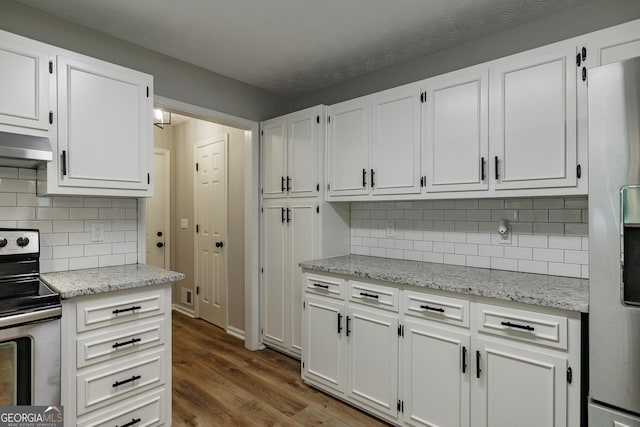 870 Rutherford Dr, Dacula, GA 30019 - kitchen featuring stainless steel appliances, wall chimney exhaust hood, white cabinetry, dark wood-style flooring, and light stone countertops